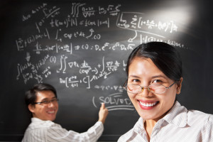 Female student solving mathematical problem on black board