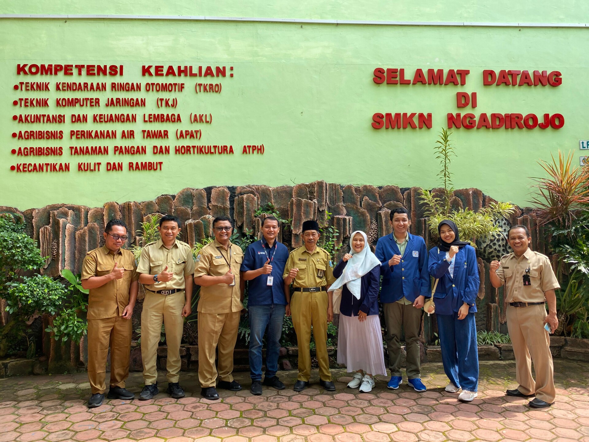 Group of school staff and project participants posing outside SMKN Ngadirojo in Indonesia.